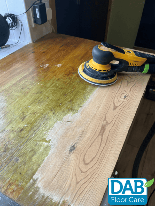 Sanding a wooden kitchen worktop surface.