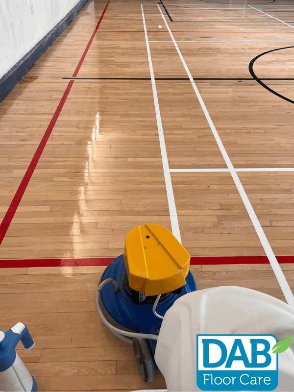 Cleaning a polished wooden gym floor.