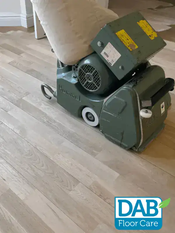 Floor sander on wooden floorboards.